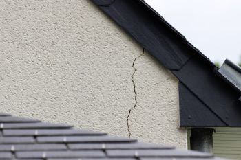 Crack running down exterior house wall near the roofline and guttering