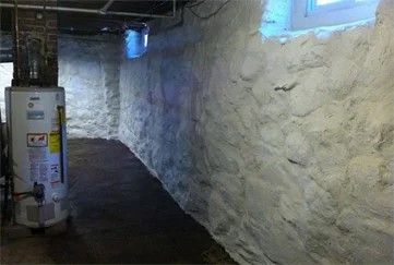 Basement waterproofing with sealed stone walls and a water heater in a finished basement